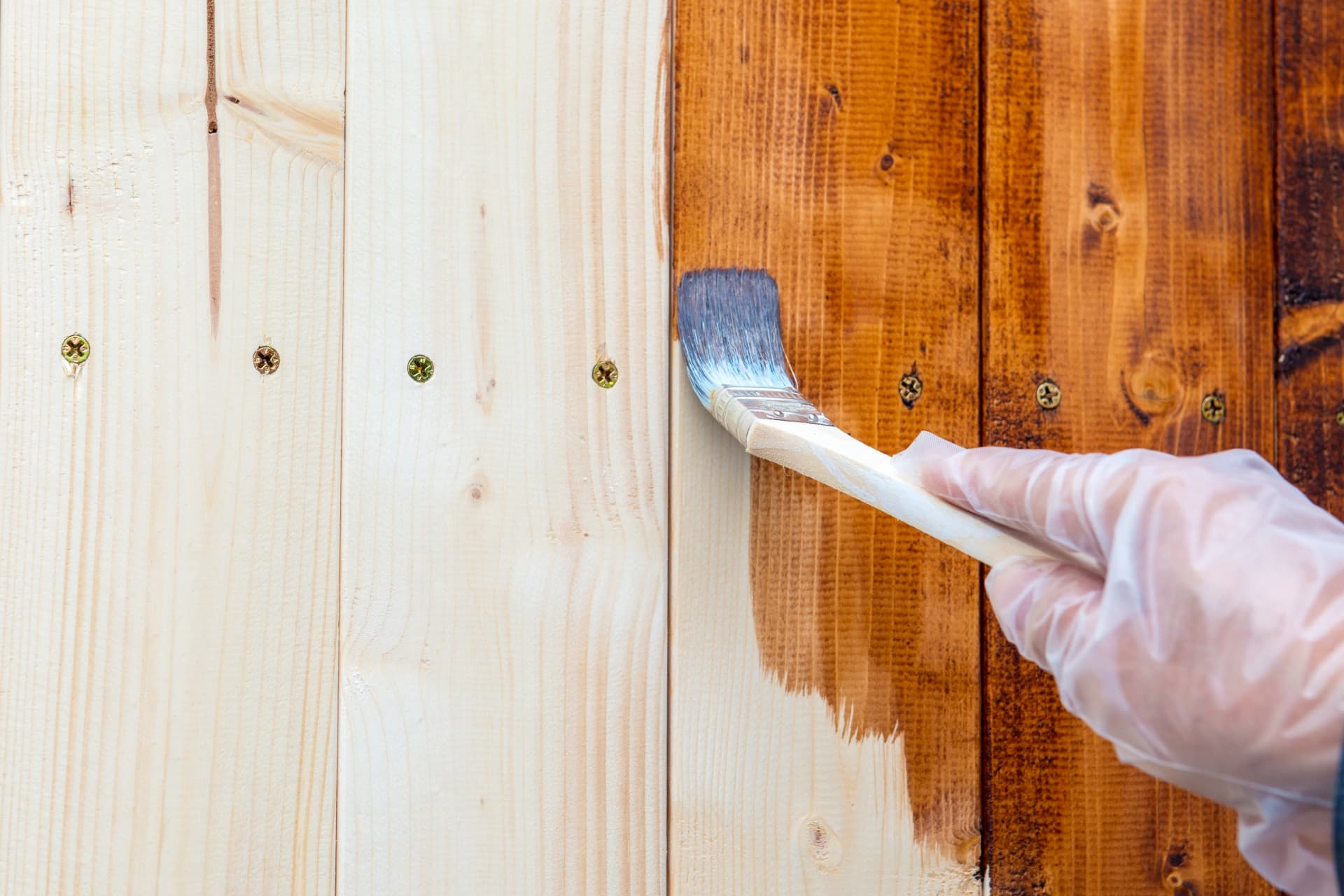 木材の表面に塗料を塗布している塗装仕上げ作業の様子