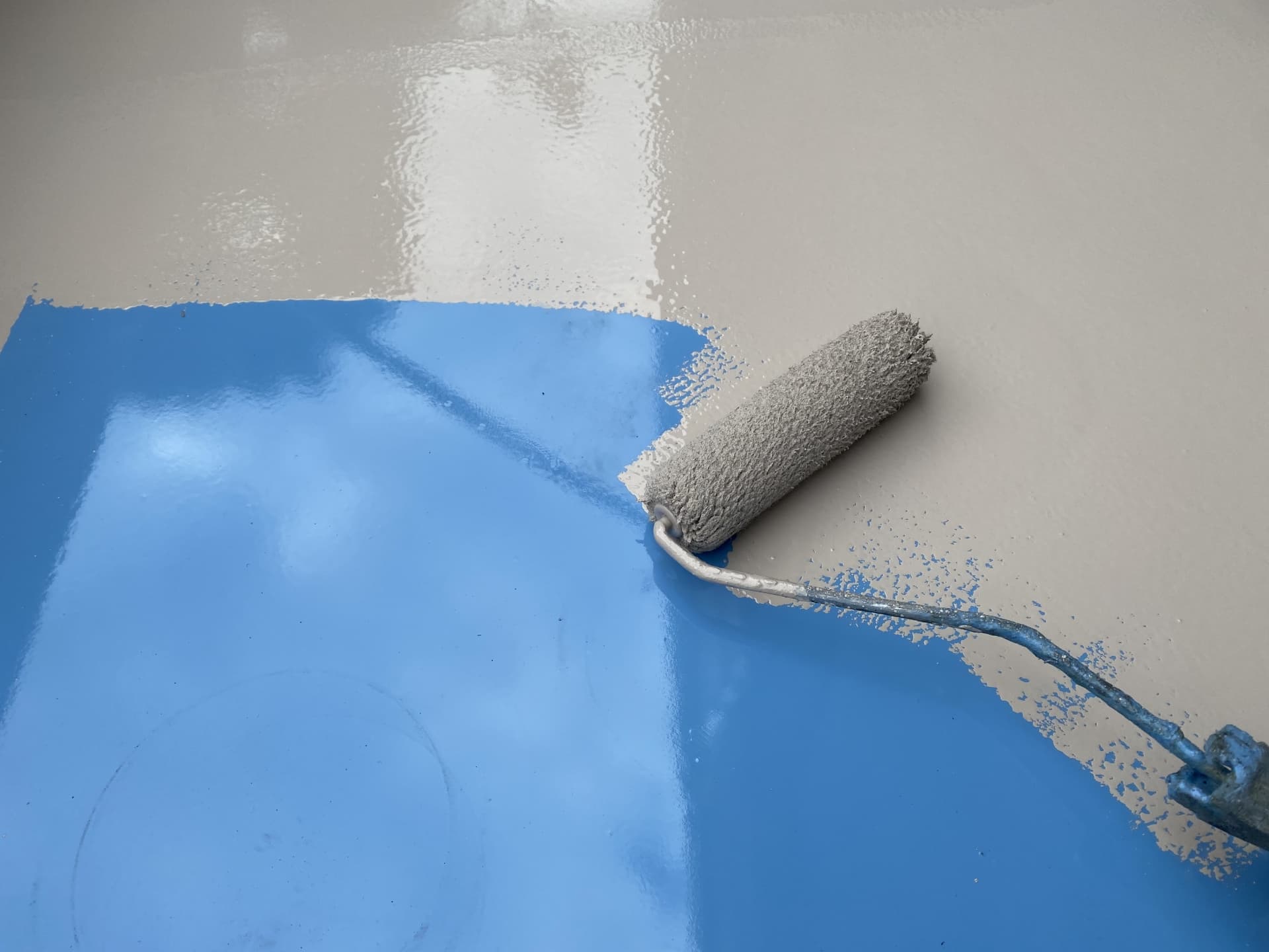 床面にウレタン防水材をローラーで塗布している施工状況