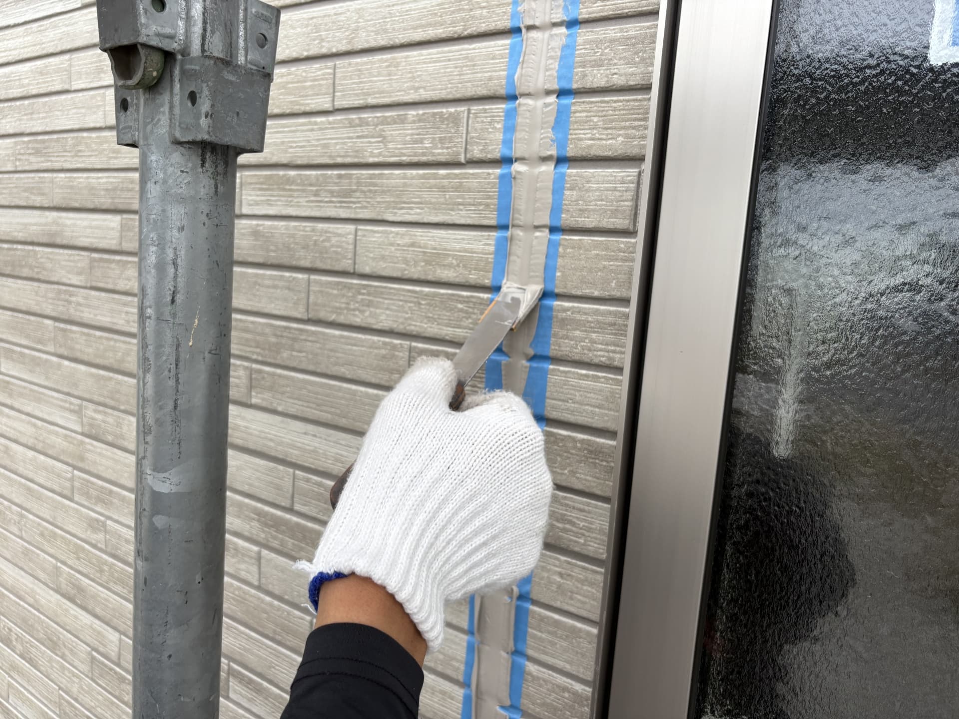 外壁目地にコーキング材を充填しヘラで均している施工作業の様子